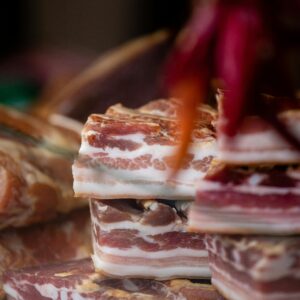 A heap of stacked raw bacon slices, showcasing intricate marbling and texture.