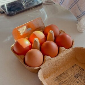 Brown eggs in a carton on a sunlit kitchen counter with a cozy, homey feel.