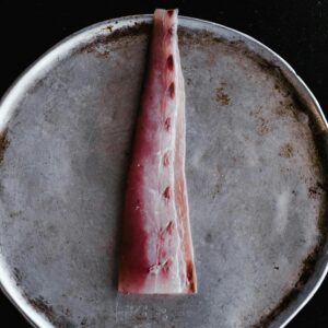 Close-up of raw fish fillet on a rustic metal plate in dramatic lighting.